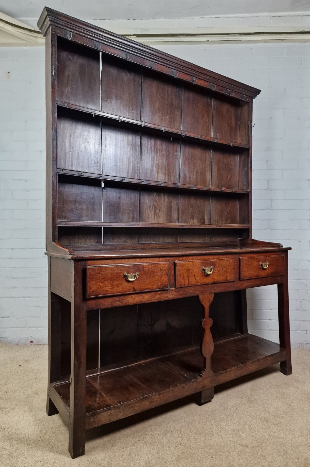 An 18th-century George II oak dresser featuring a top open plate rack above three frieze drawers and an open lower pot shelf. View VI
