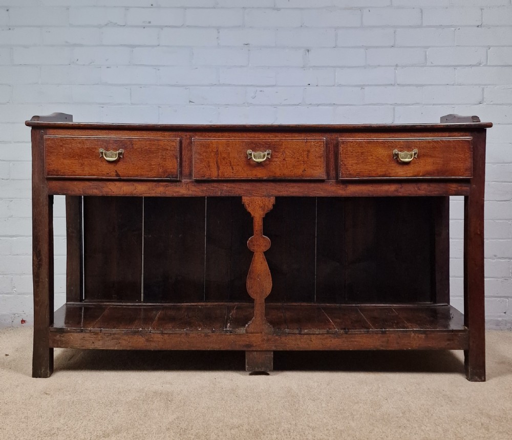 An 18th-century George II oak dresser featuring a top open plate rack above three frieze drawers and an open lower pot shelf. View IX