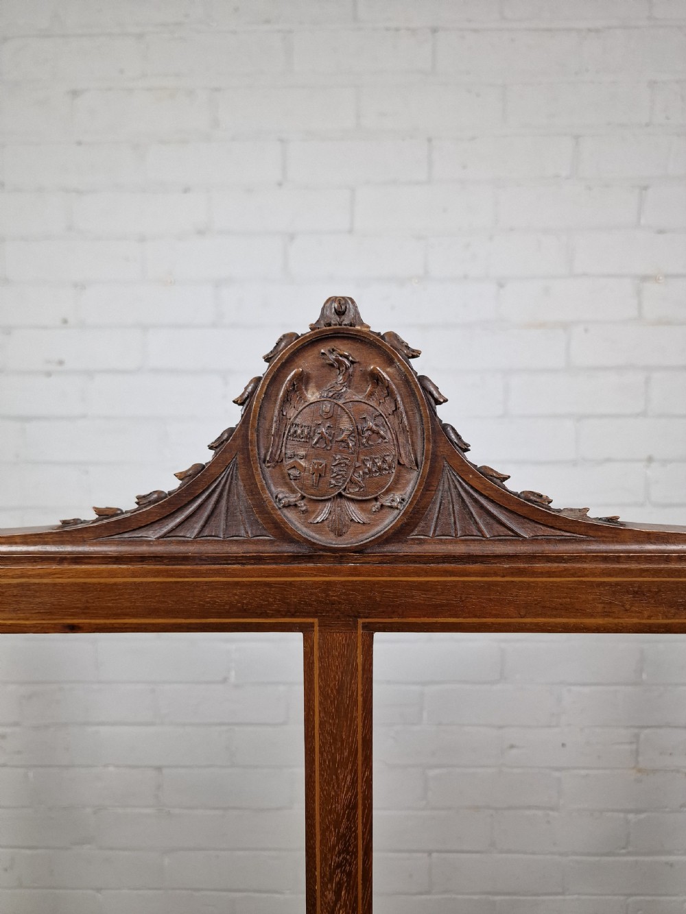 An Edwardian three-panel mahogany folding screen featuring a central carved crest, glazed grid panes, and bracket feet. View II