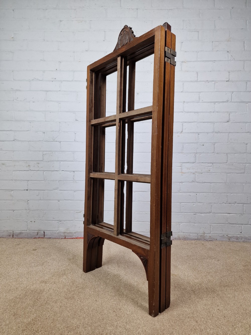 An Edwardian three-panel mahogany folding screen featuring a central carved crest, glazed grid panes, and bracket feet. View III