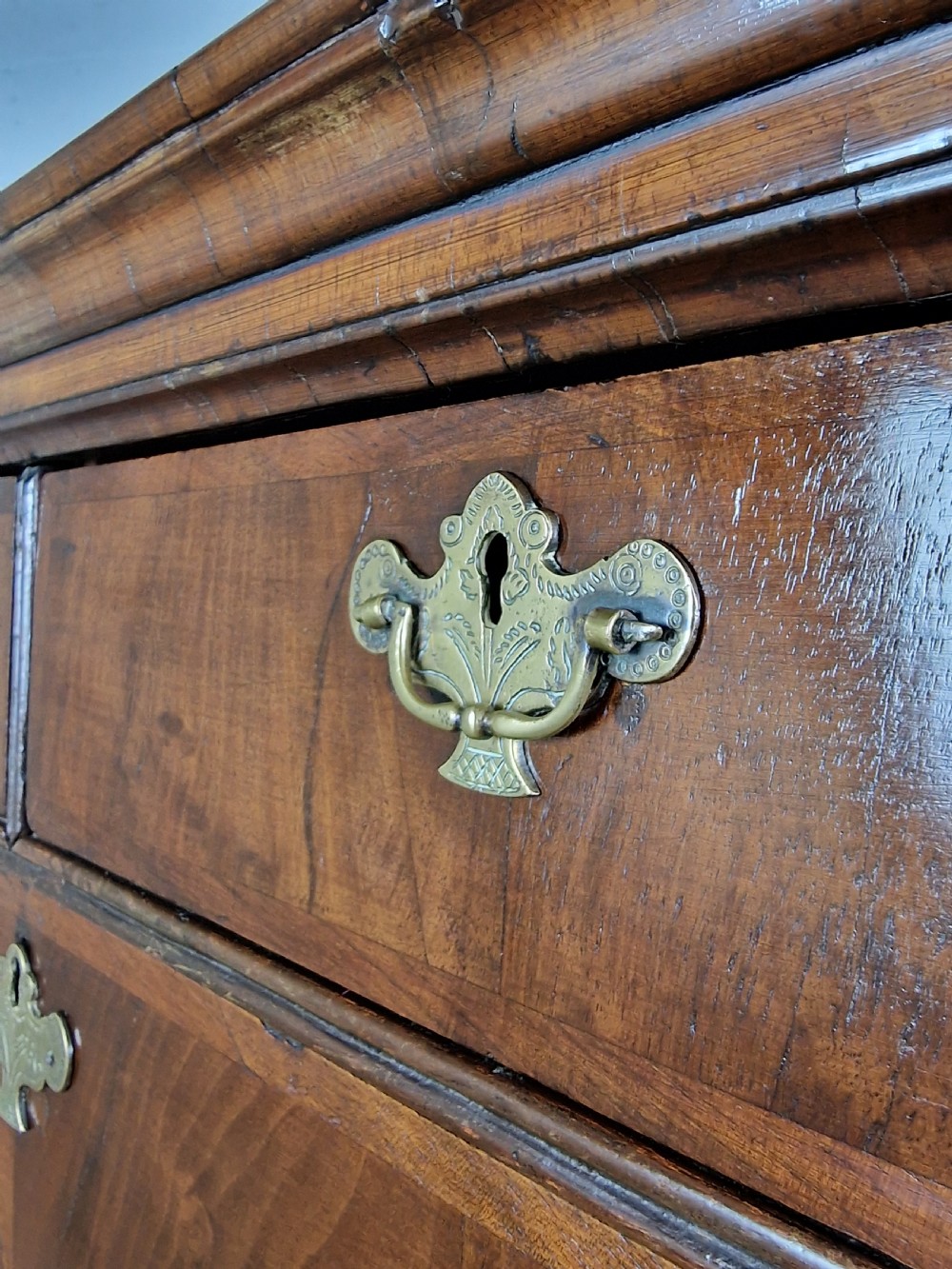 An early eighteenth-century Georgian walnut secretaire chest on chest featuring brass drop handles, a drop-front desk compartment with fitted pigeonholes, and bracket feet. View IV