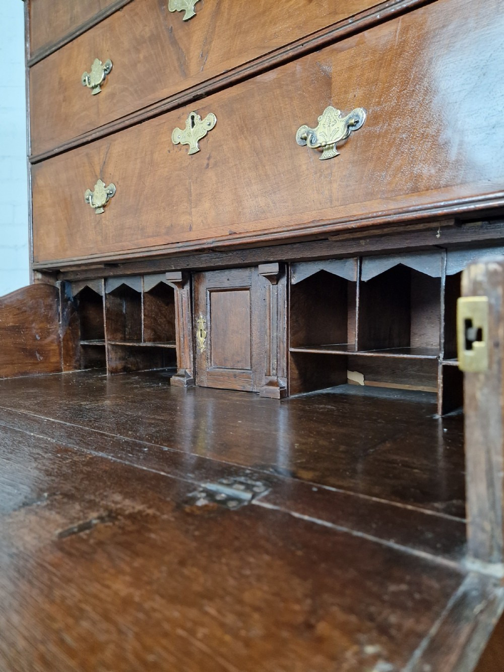 An early eighteenth-century Georgian walnut secretaire chest on chest featuring brass drop handles, a drop-front desk compartment with fitted pigeonholes, and bracket feet. View VII