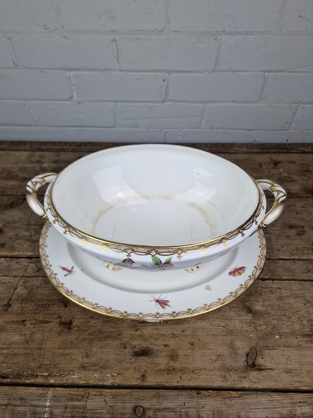 An antique white porcelain soup tureen featuring hand-painted bird motifs, gilded scroll handles, four scroll feet, and a matching underplate. View III