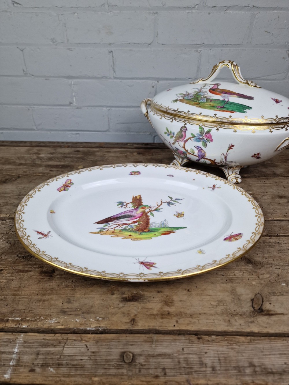 An antique white porcelain soup tureen featuring hand-painted bird motifs, gilded scroll handles, four scroll feet, and a matching underplate. View IV