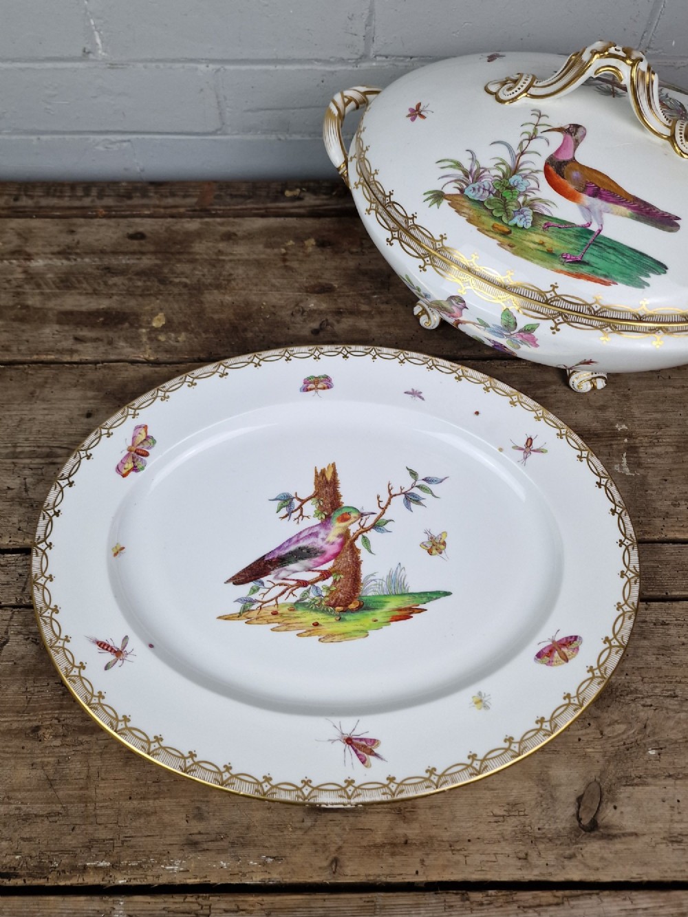 An antique white porcelain soup tureen featuring hand-painted bird motifs, gilded scroll handles, four scroll feet, and a matching underplate. View V