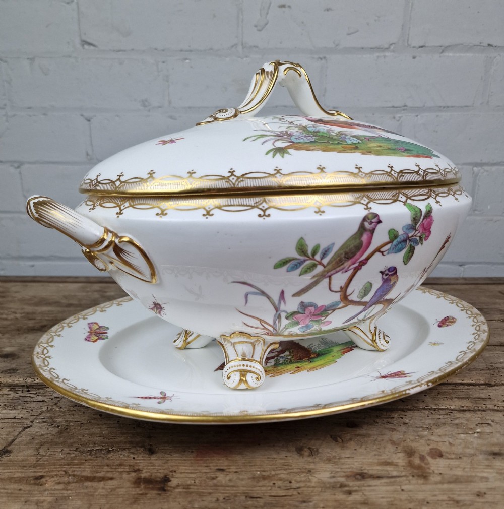 An antique white porcelain soup tureen featuring hand-painted bird motifs, gilded scroll handles, four scroll feet, and a matching underplate. View VII