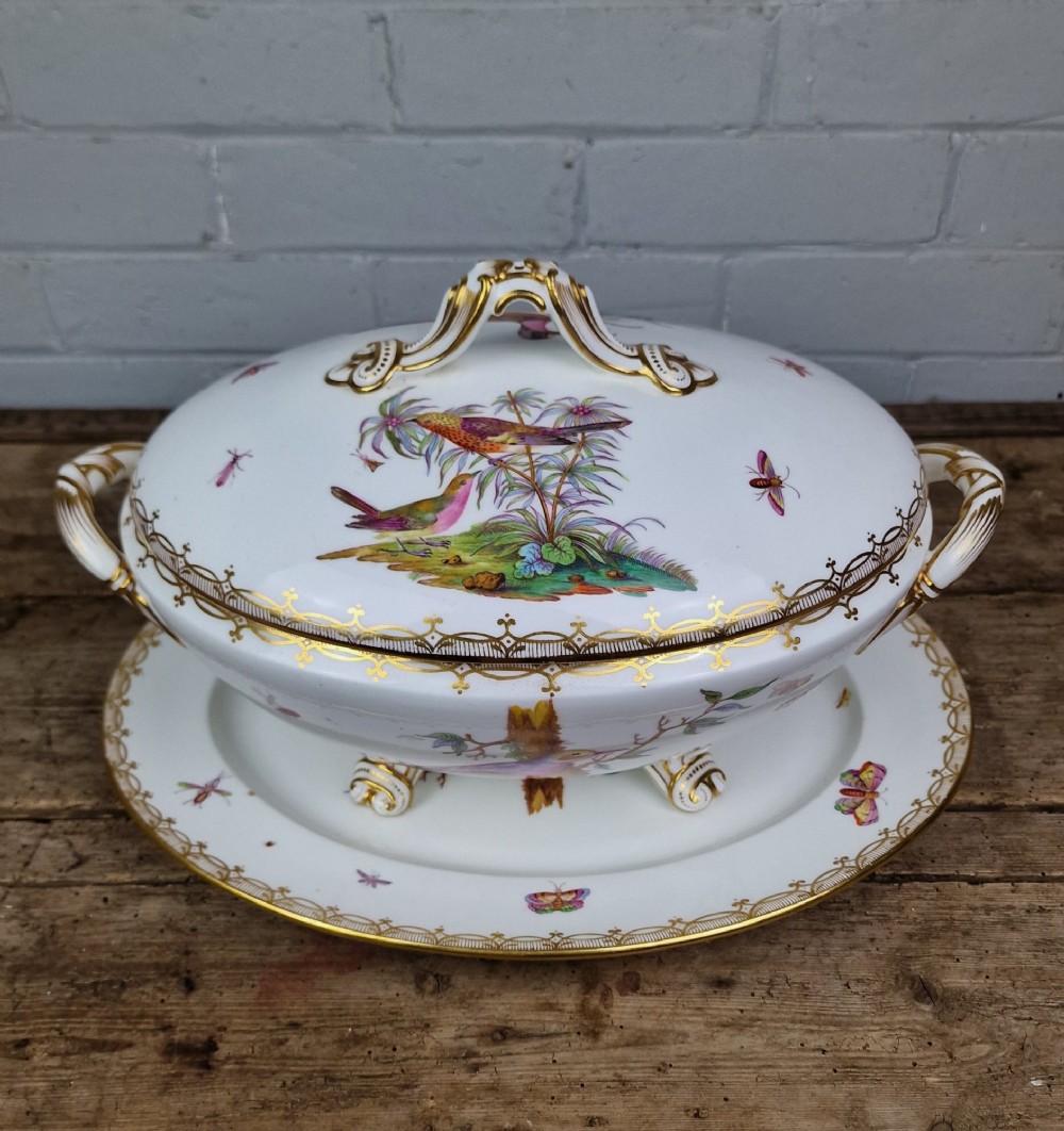An antique white porcelain soup tureen featuring hand-painted bird motifs, gilded scroll handles, four scroll feet, and a matching underplate. View XII