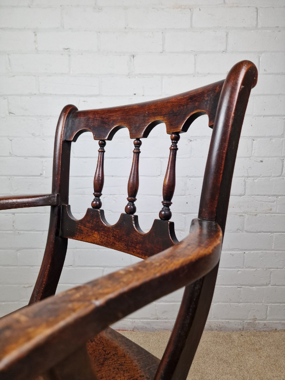 A Victorian dark brown elm and beech Oxford bar back Windsor armchair featuring turned spindles, shaped armrests, and turned legs with stretchers. View II