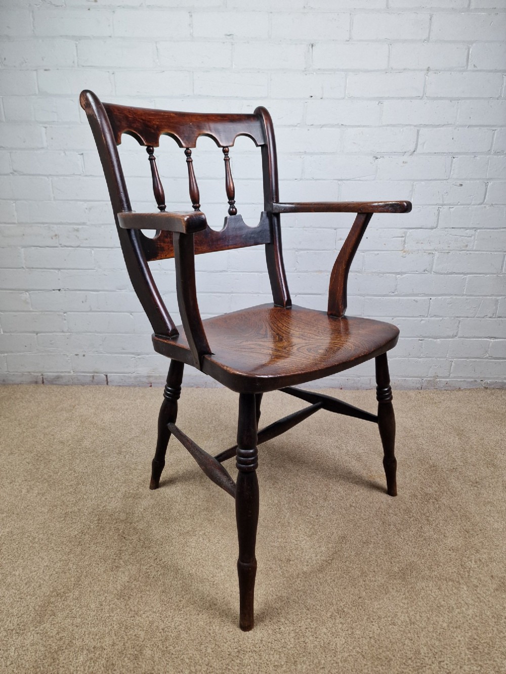 A Victorian dark brown elm and beech Oxford bar back Windsor armchair featuring turned spindles, shaped armrests, and turned legs with stretchers. View III