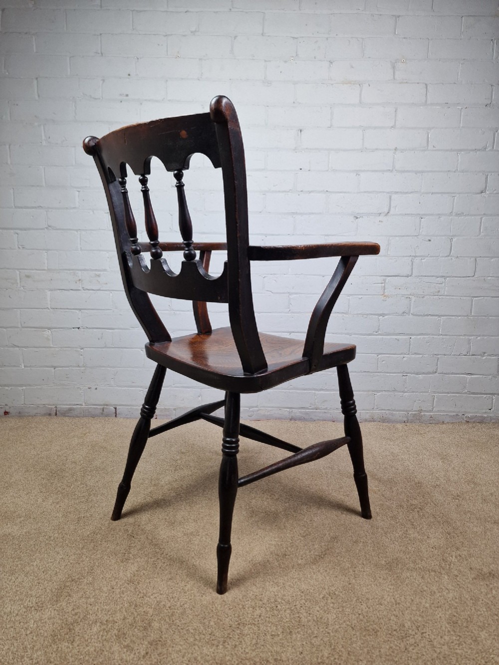 A Victorian dark brown elm and beech Oxford bar back Windsor armchair featuring turned spindles, shaped armrests, and turned legs with stretchers. View V