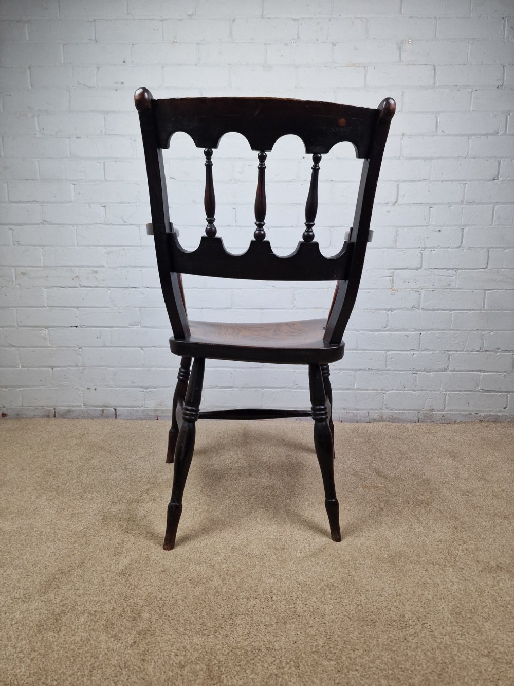 A Victorian dark brown elm and beech Oxford bar back Windsor armchair featuring turned spindles, shaped armrests, and turned legs with stretchers. View VI