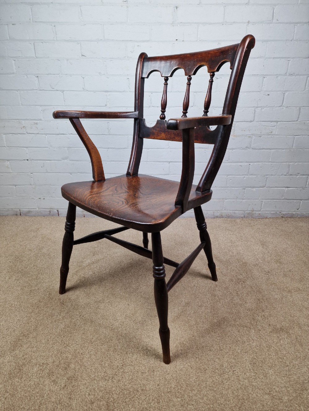 A Victorian dark brown elm and beech Oxford bar back Windsor armchair featuring turned spindles, shaped armrests, and turned legs with stretchers. View X