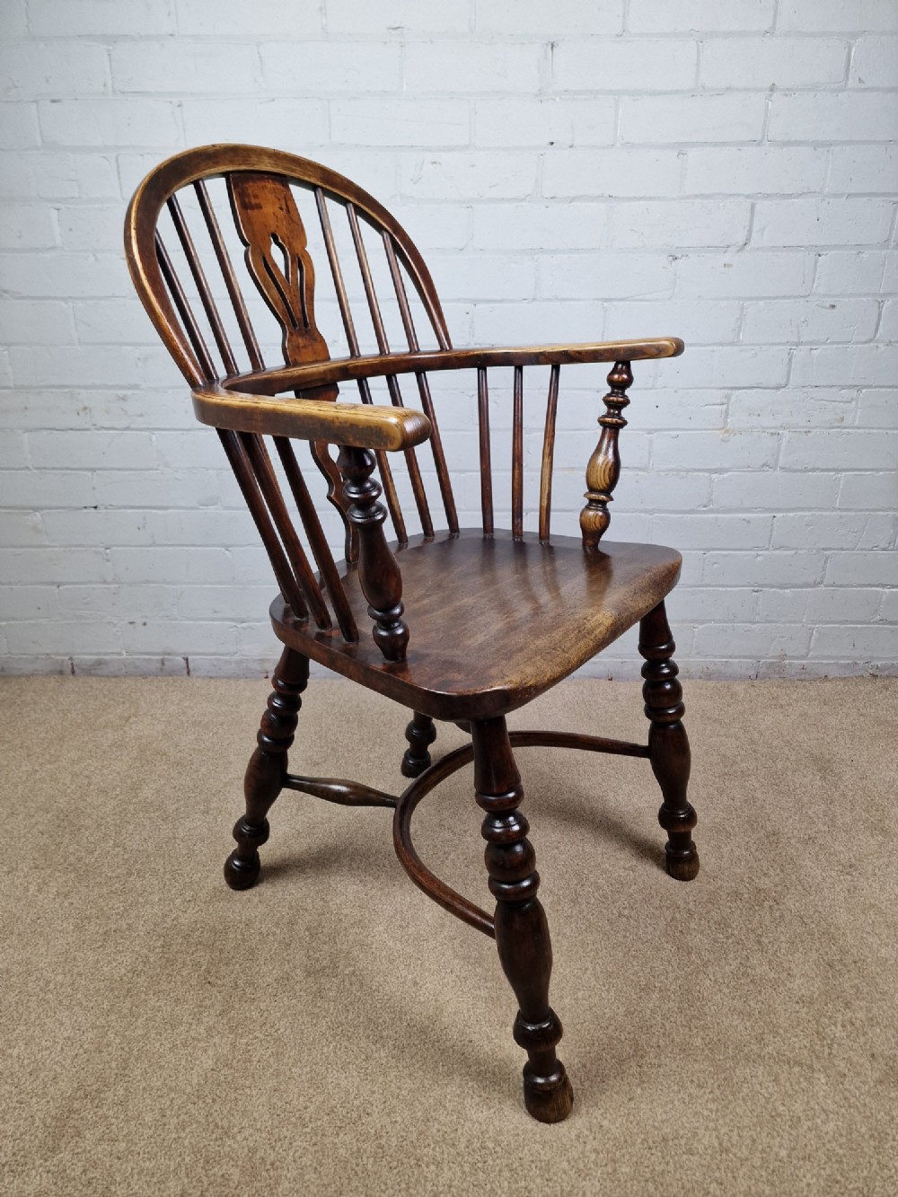 A 19th-century low-back wooden Windsor armchair featuring a curved top rail, pierced central splat, vertical spindles, turned legs, and a crinoline stretcher. View II
