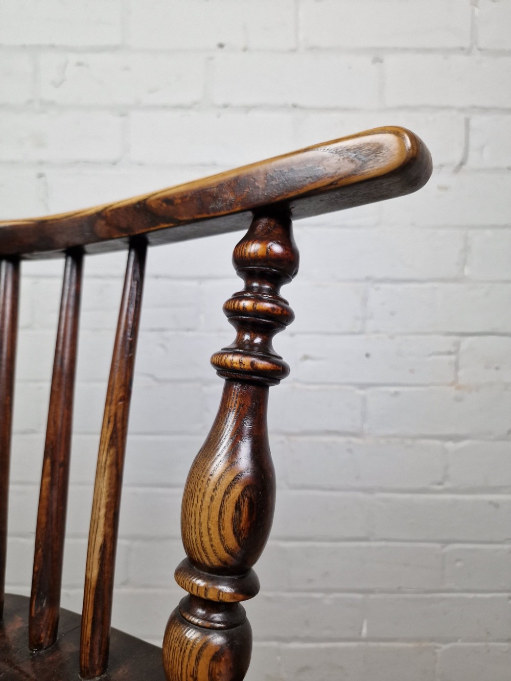 A 19th-century low-back wooden Windsor armchair featuring a curved top rail, pierced central splat, vertical spindles, turned legs, and a crinoline stretcher. View III
