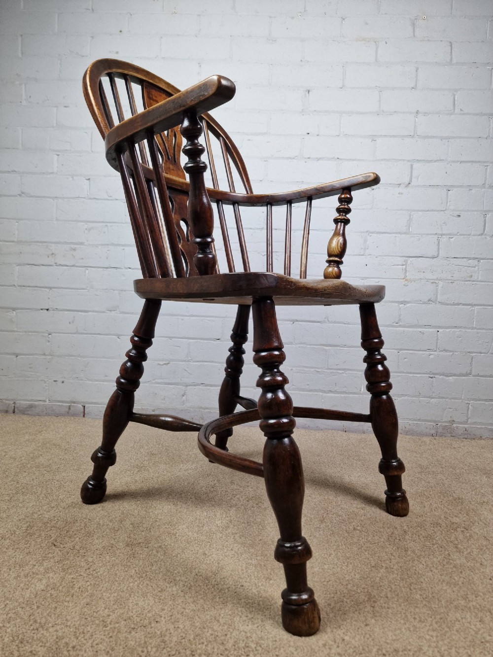 A 19th-century low-back wooden Windsor armchair featuring a curved top rail, pierced central splat, vertical spindles, turned legs, and a crinoline stretcher. View IV