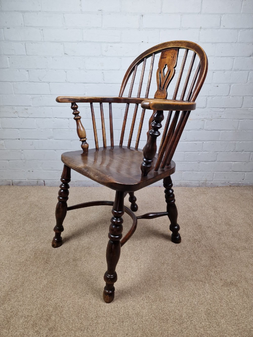 A 19th-century low-back wooden Windsor armchair featuring a curved top rail, pierced central splat, vertical spindles, turned legs, and a crinoline stretcher. View VIII