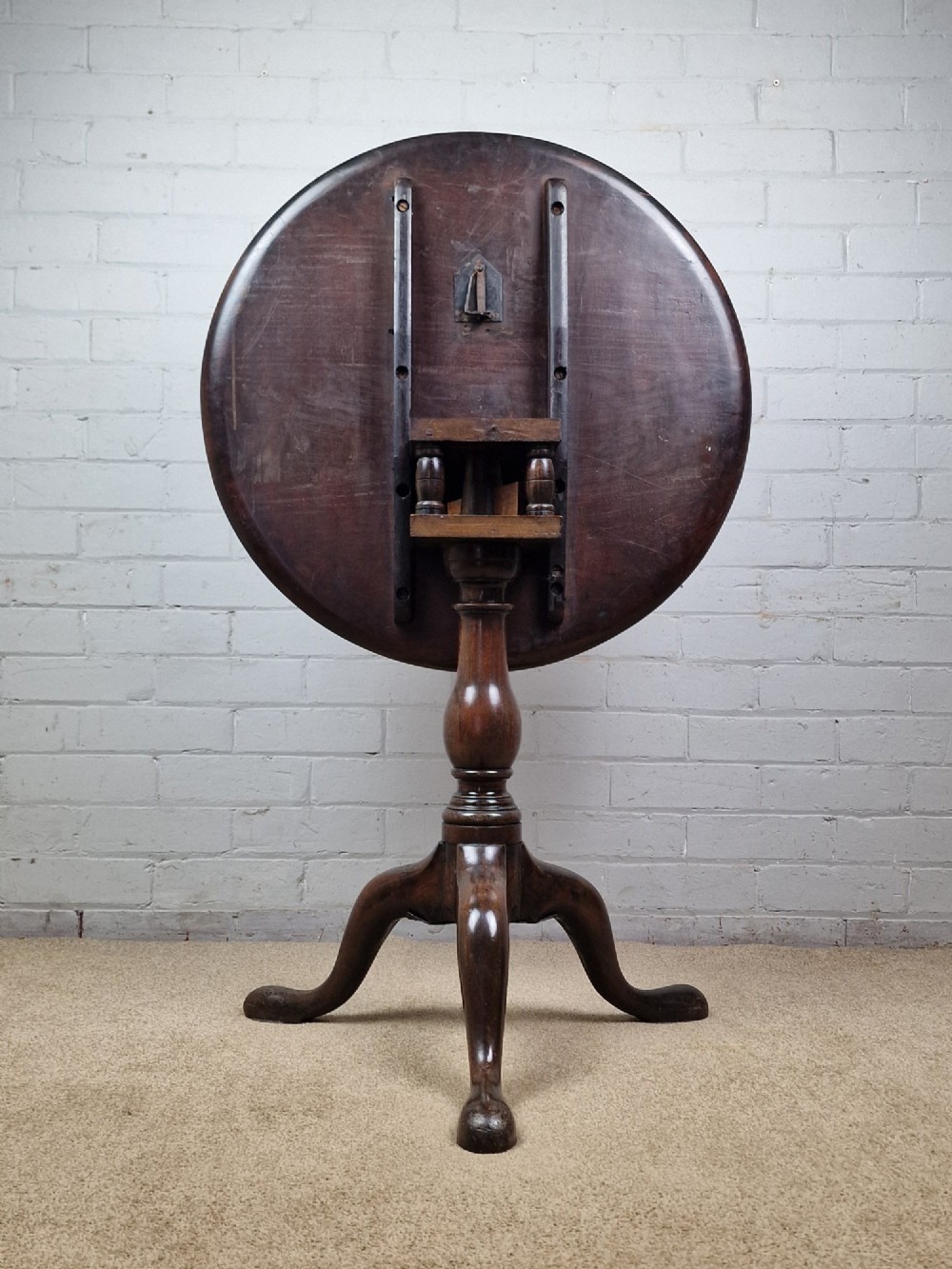 A late eighteenth-century Georgian mahogany tripod table shown with its circular dished top tilted vertically above a turned baluster pedestal on three cabriole legs. View III
