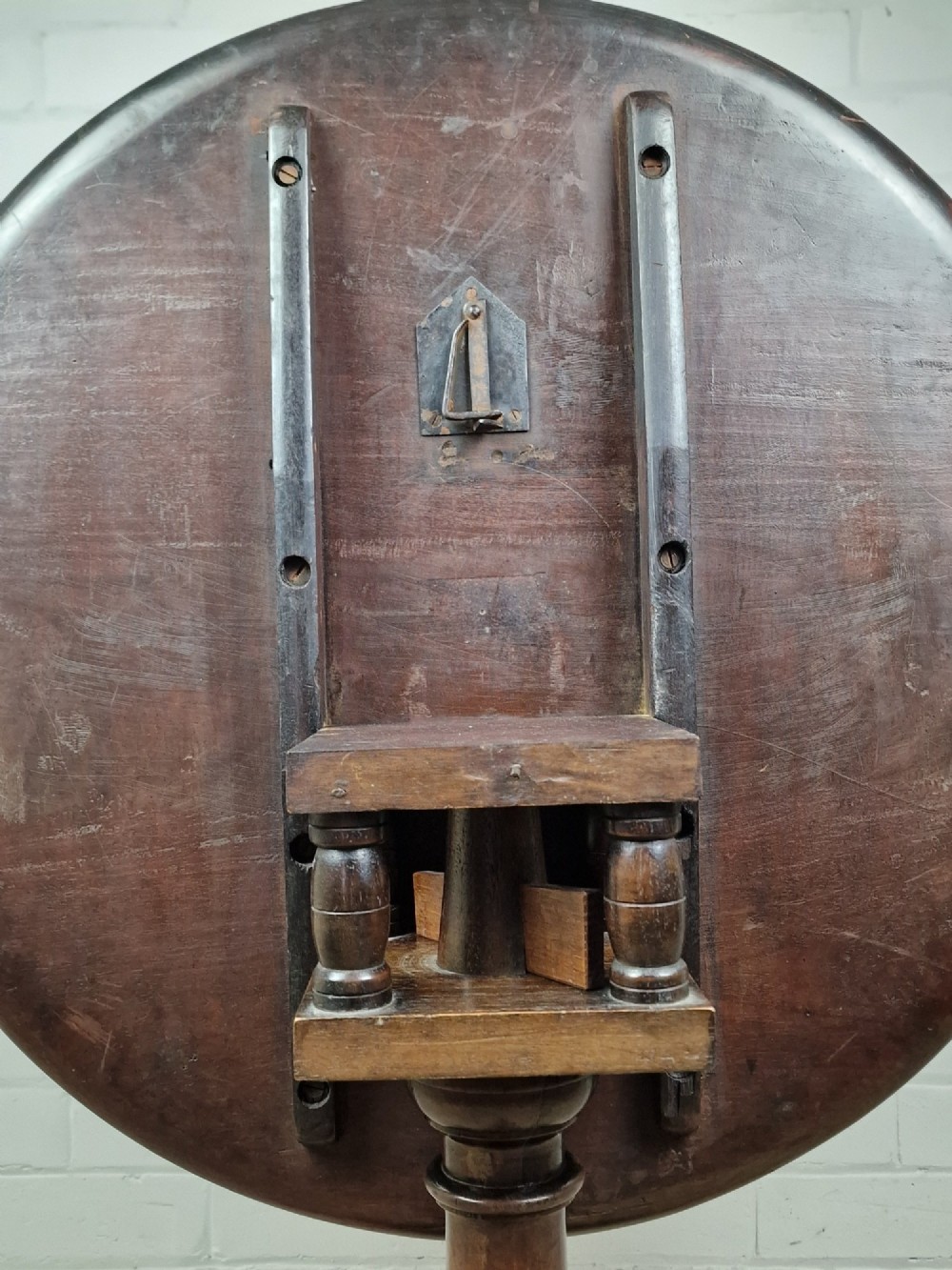 A late eighteenth-century Georgian mahogany tripod table shown with its circular dished top tilted vertically above a turned baluster pedestal on three cabriole legs. View IV