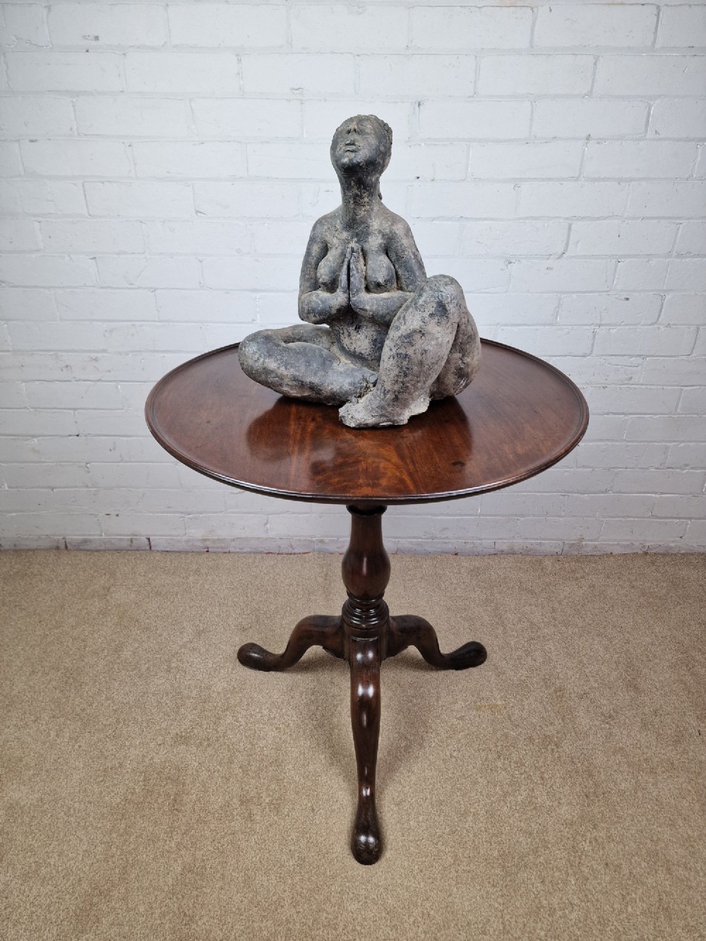 A late eighteenth-century Georgian mahogany tripod table shown with its circular dished top tilted vertically above a turned baluster pedestal on three cabriole legs. View VI