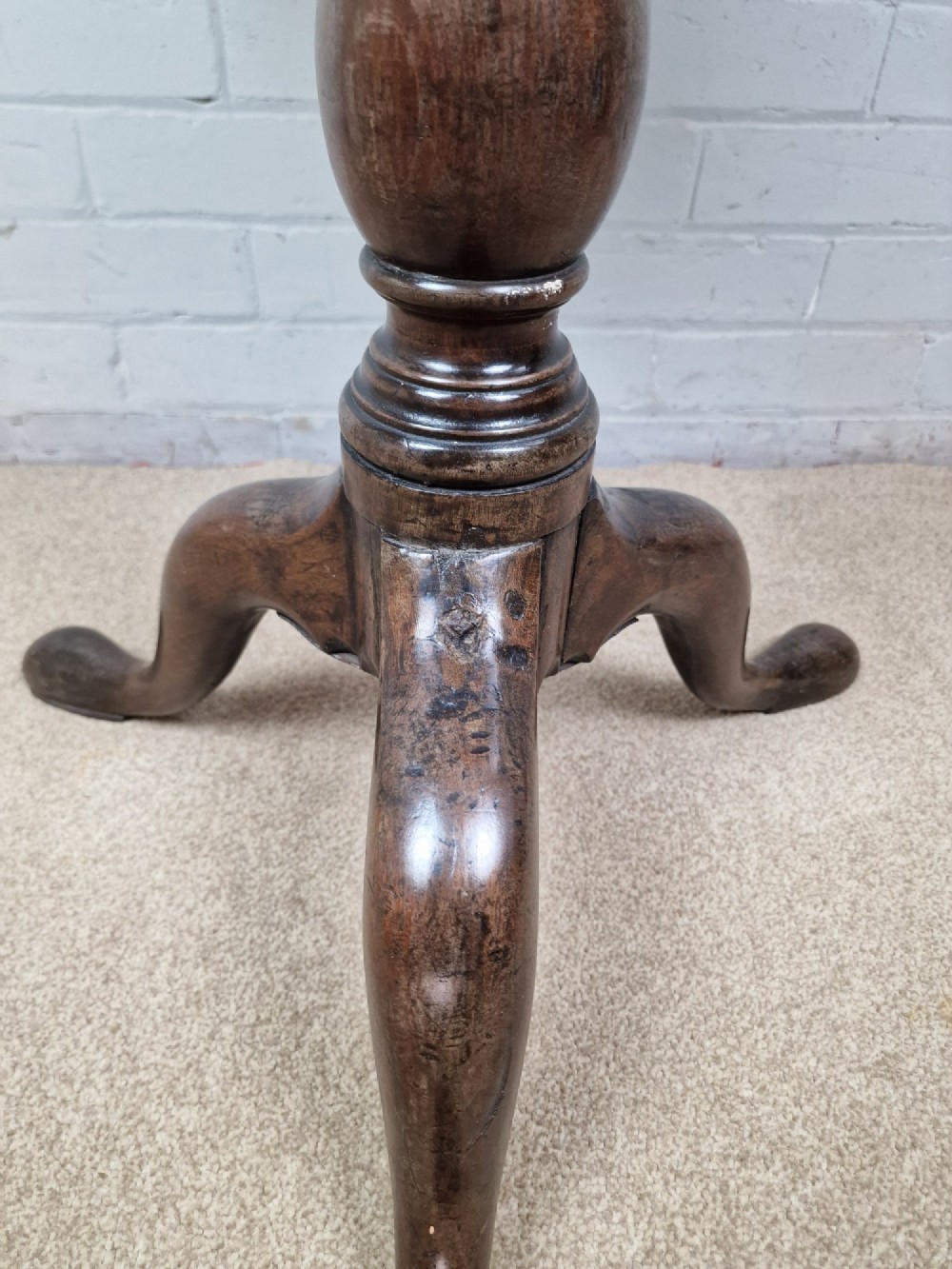 A late eighteenth-century Georgian mahogany tripod table shown with its circular dished top tilted vertically above a turned baluster pedestal on three cabriole legs. View VII