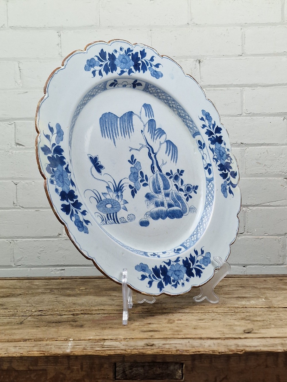 An 18th-century English Delftware charger featuring cobalt blue chinoiserie landscape hand-painted on a white scalloped earthenware platter. View III