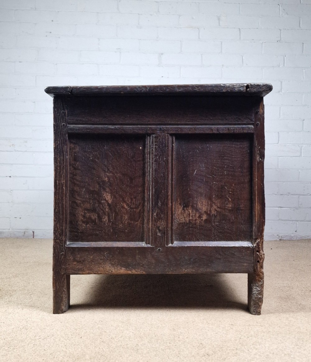 A late 17th-century dark oak coffer with a hinged lid, featuring three carved front panels and an intricate carved top frieze. View IX