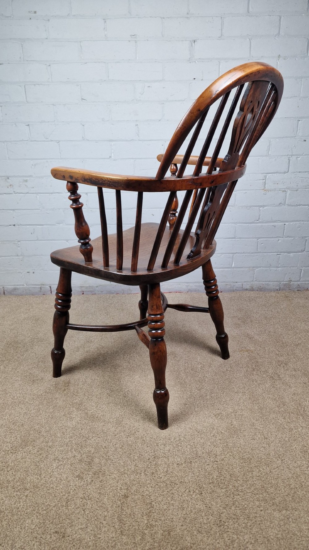 A 19th-century Nottinghamshire Windsor armchair featuring a hoop back with a pierced splat, shaped elm saddle seat, steam-bent yew bow, and turned legs. View V
