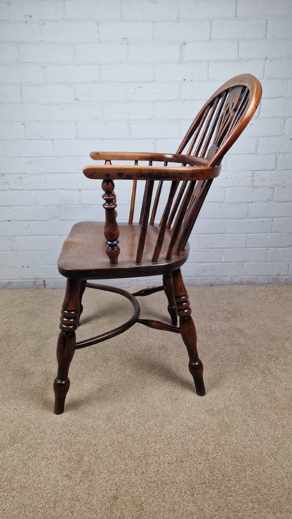 A 19th-century Nottinghamshire Windsor armchair featuring a hoop back with a pierced splat, shaped elm saddle seat, steam-bent yew bow, and turned legs. View VI