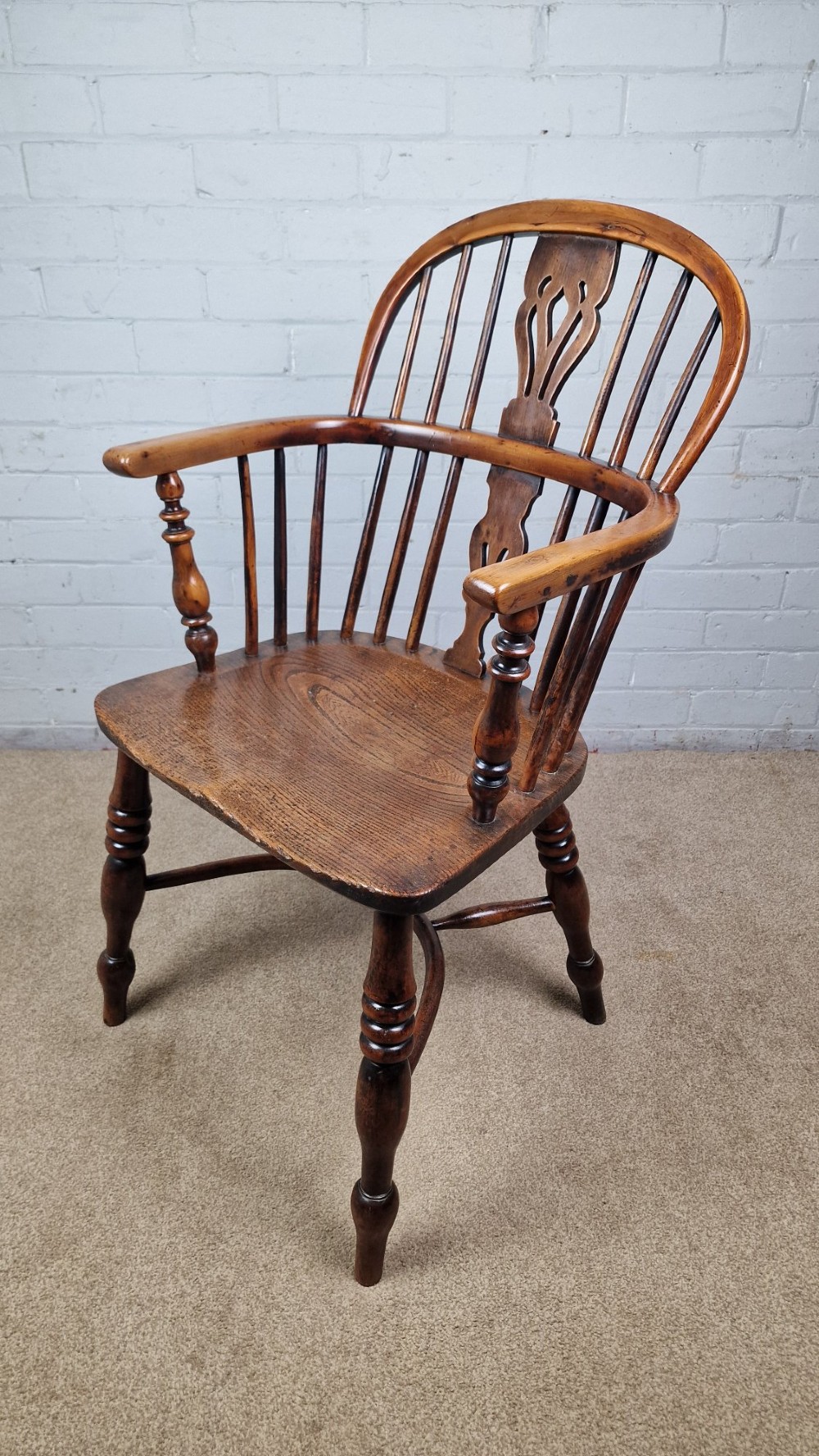 A 19th-century Nottinghamshire Windsor armchair featuring a hoop back with a pierced splat, shaped elm saddle seat, steam-bent yew bow, and turned legs.