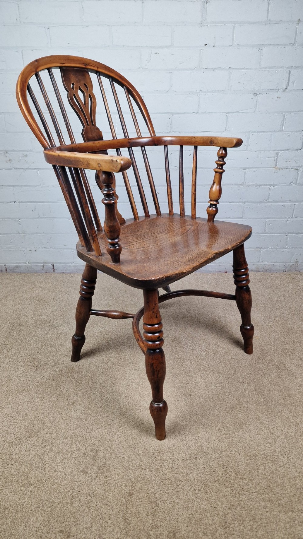 A 19th-century Nottinghamshire Windsor armchair featuring a hoop back with a pierced splat, shaped elm saddle seat, steam-bent yew bow, and turned legs. View X