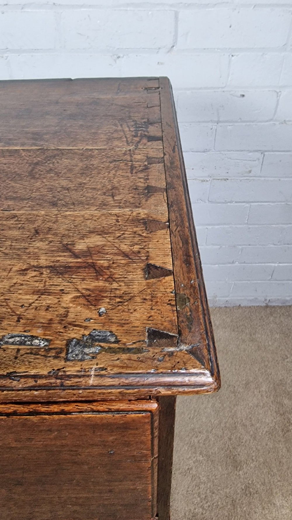 An 18th-century dark oak chest of drawers featuring two wide drawers with brass handles, standing on shaped bracket feet. View II