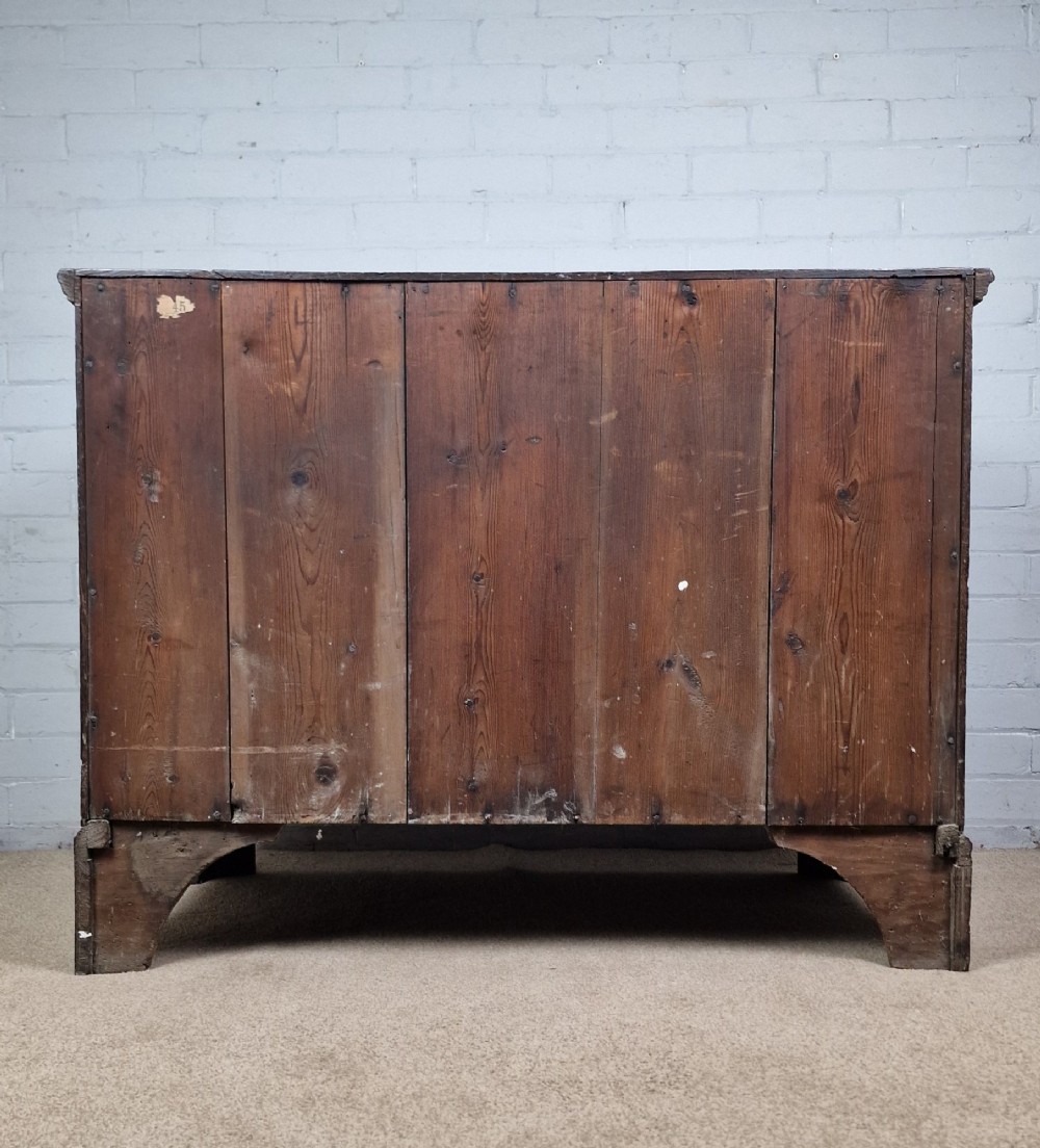 An 18th-century dark oak chest of drawers featuring two wide drawers with brass handles, standing on shaped bracket feet. View VII