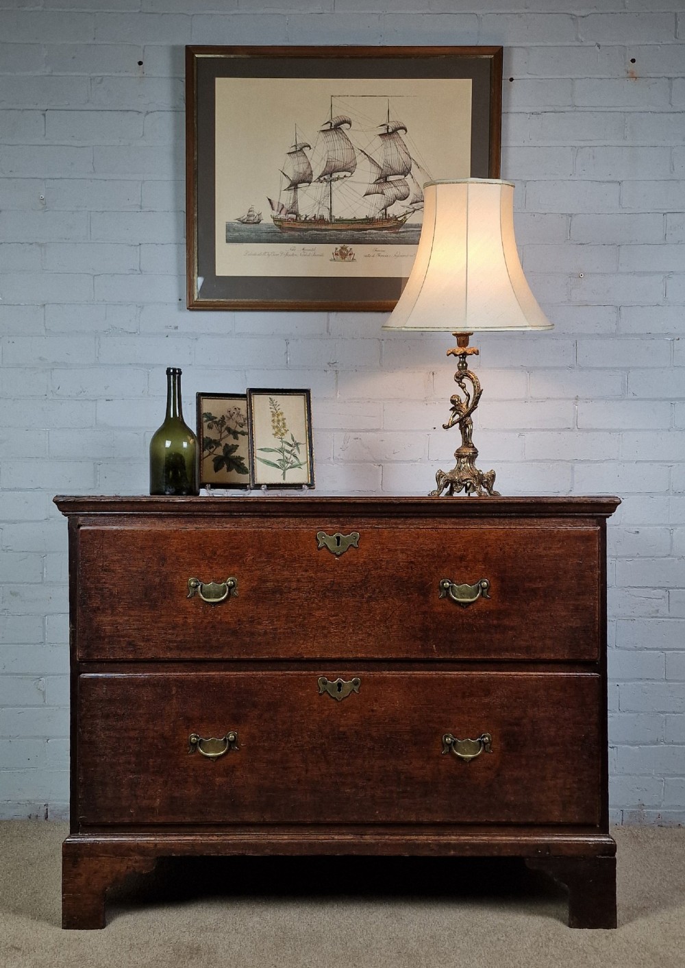 An 18th-century dark oak chest of drawers featuring two wide drawers with brass handles, standing on shaped bracket feet. View VIII
