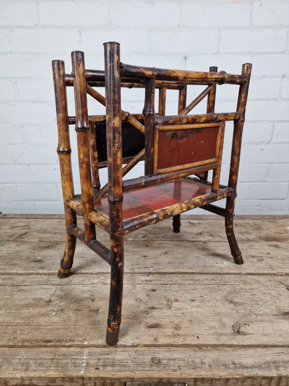 A nineteenth-century tiger bamboo magazine rack featuring a mottled cane frame with lacquered side panels.