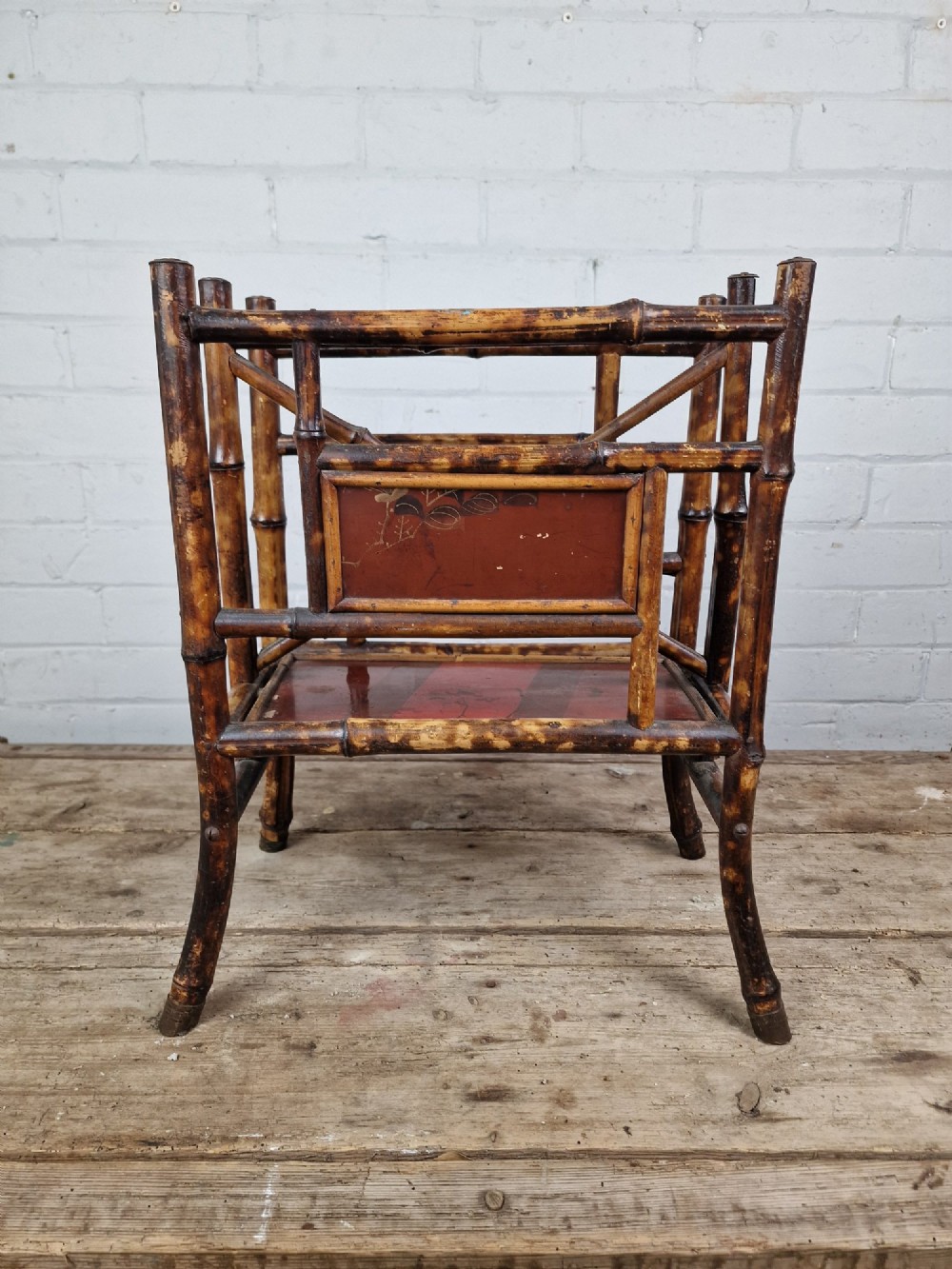 A nineteenth-century tiger bamboo magazine rack featuring a mottled cane frame with lacquered side panels. View VII
