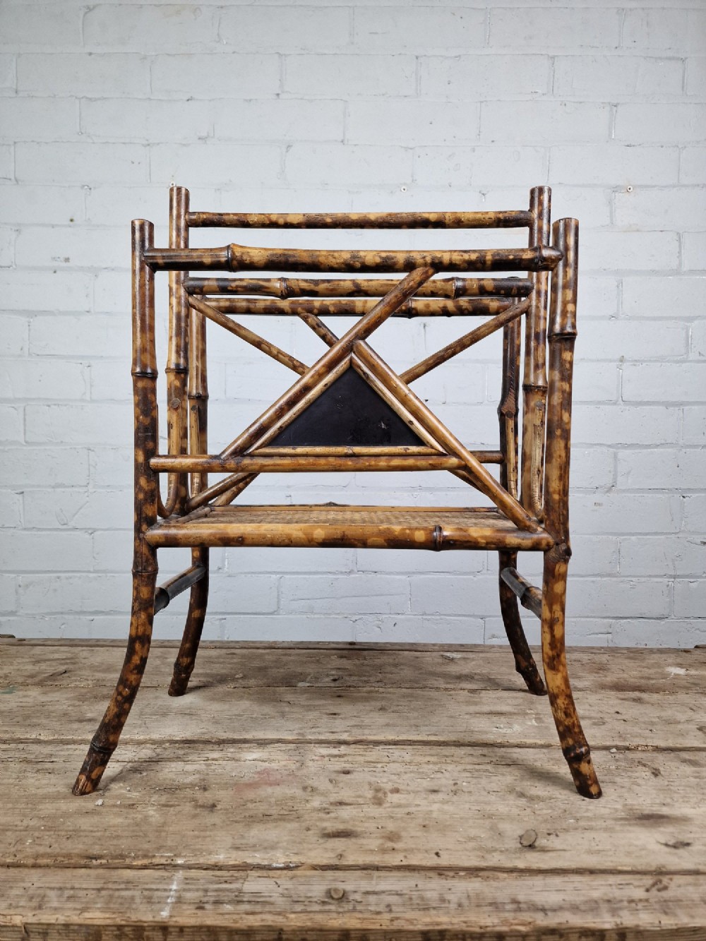 A late 19th-century Aesthetic Movement magazine rack crafted from scorched tortoiseshell bamboo with geometric triangular supports and black lacquered panels. View III