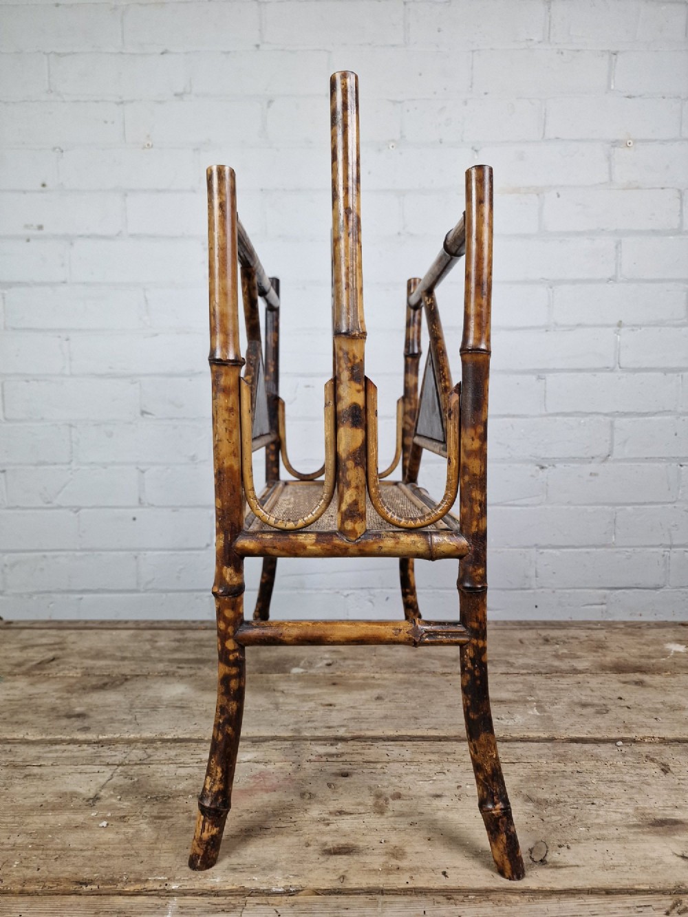 A late 19th-century Aesthetic Movement magazine rack crafted from scorched tortoiseshell bamboo with geometric triangular supports and black lacquered panels. View IV