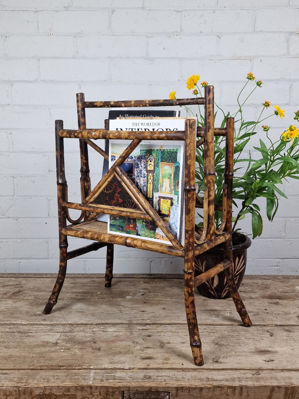 A late 19th-century Aesthetic Movement magazine rack crafted from scorched tortoiseshell bamboo with geometric triangular supports and black lacquered panels. View II