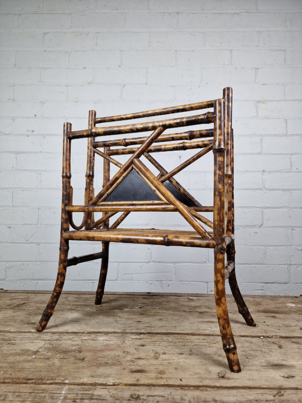 A late 19th-century Aesthetic Movement magazine rack crafted from scorched tortoiseshell bamboo with geometric triangular supports and black lacquered panels. View VI