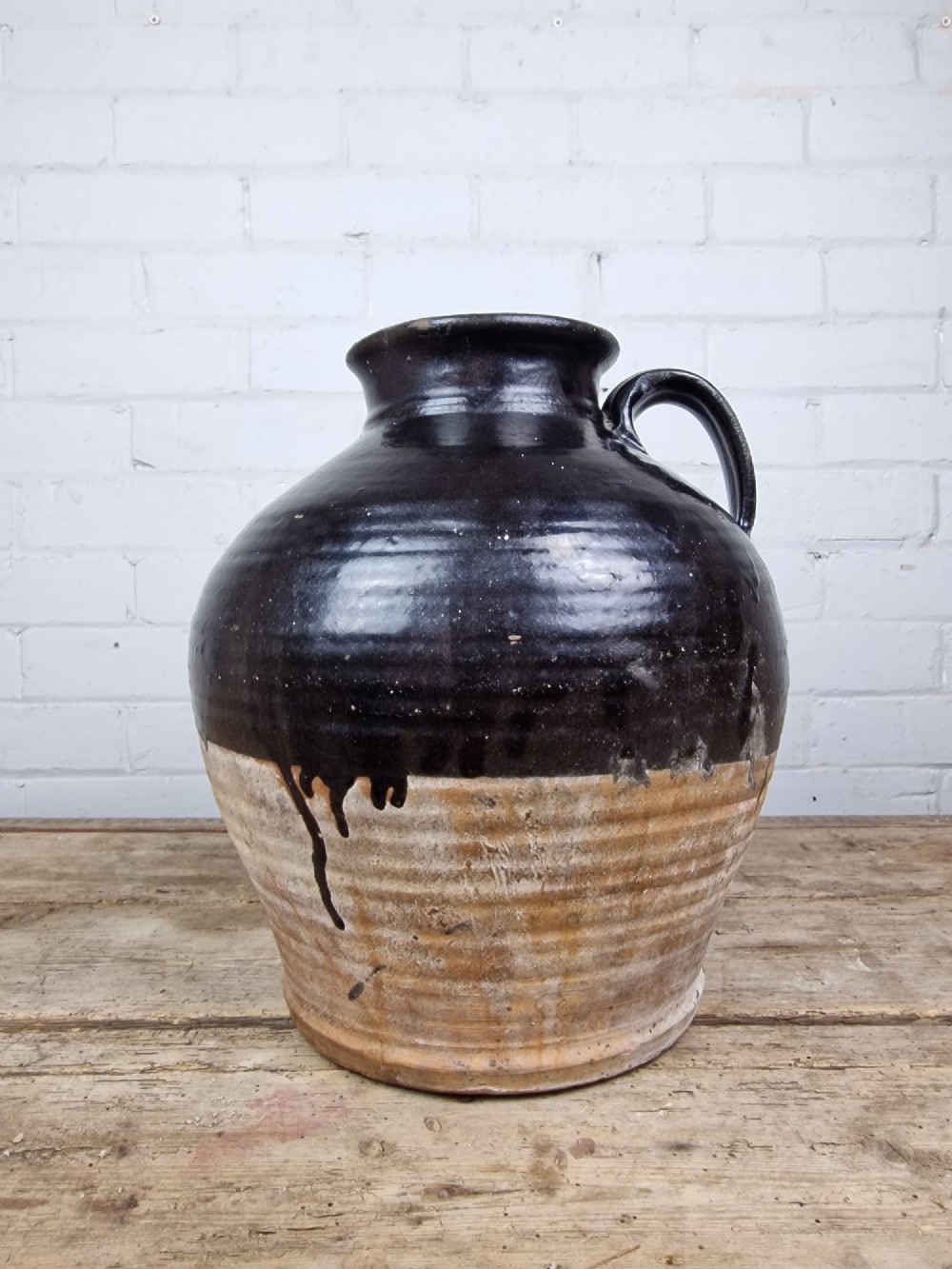 An antique late 18th or early 19th-century earthenware slipware jug featuring a dark brown glazed upper body and a textured terracotta lower base. View II