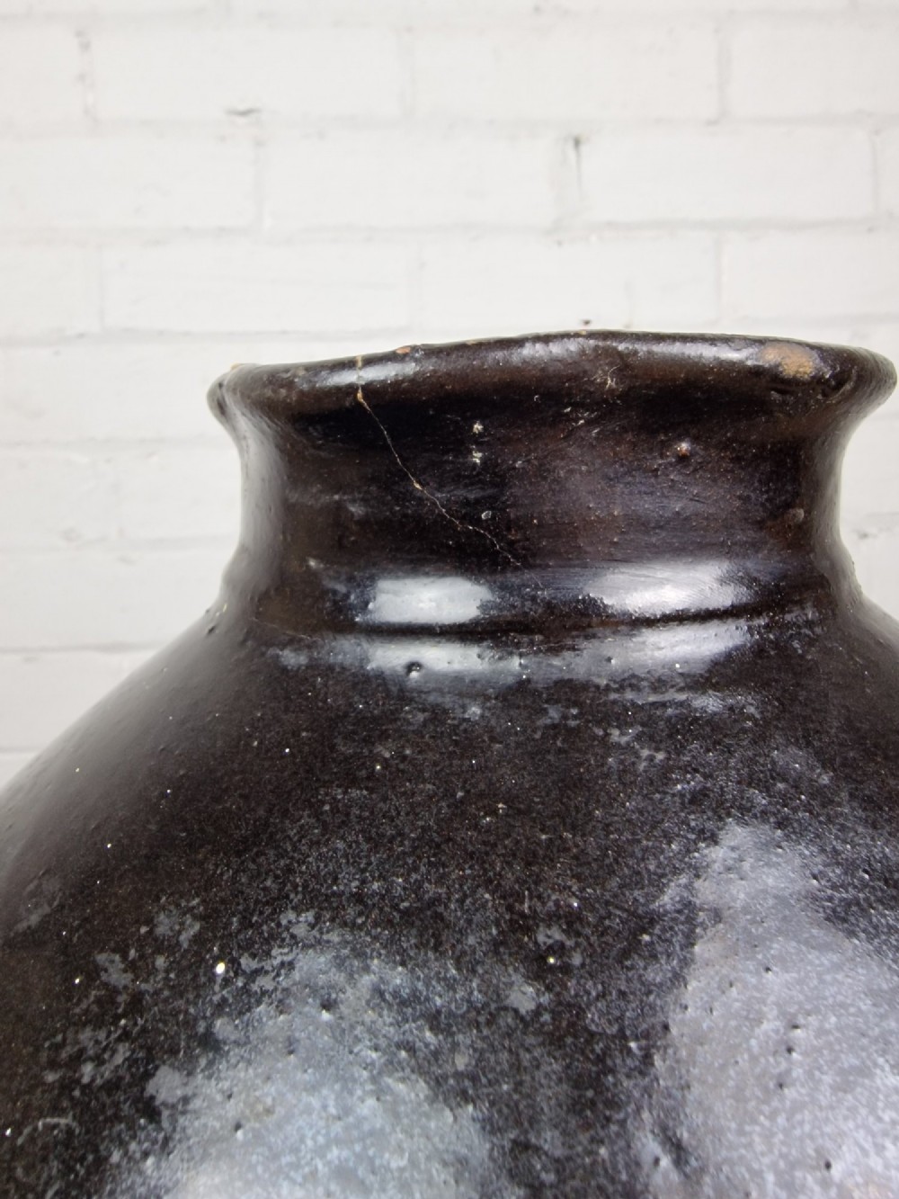 An antique late 18th or early 19th-century earthenware slipware jug featuring a dark brown glazed upper body and a textured terracotta lower base. View IV