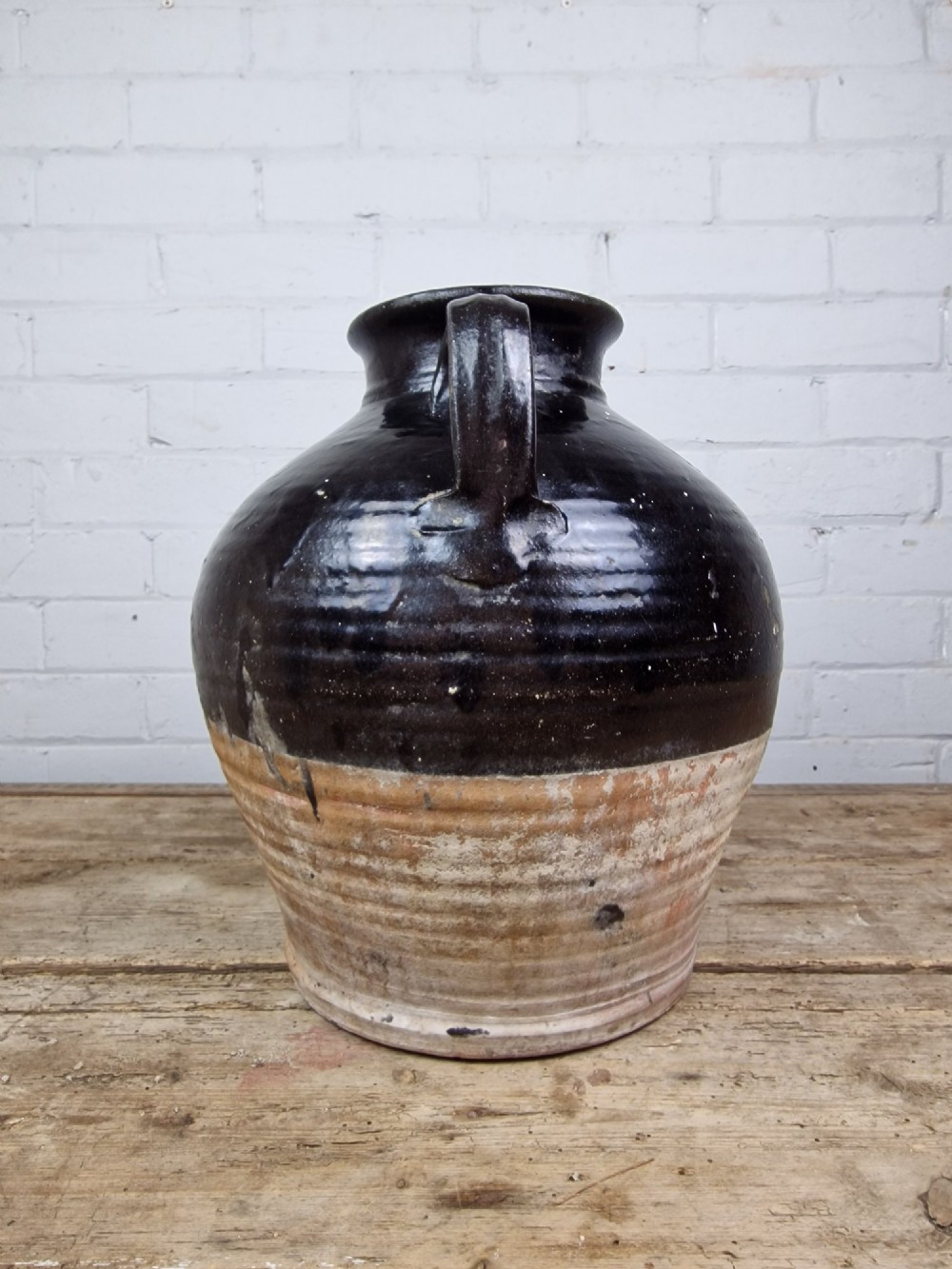 An antique late 18th or early 19th-century earthenware slipware jug featuring a dark brown glazed upper body and a textured terracotta lower base. View VIII
