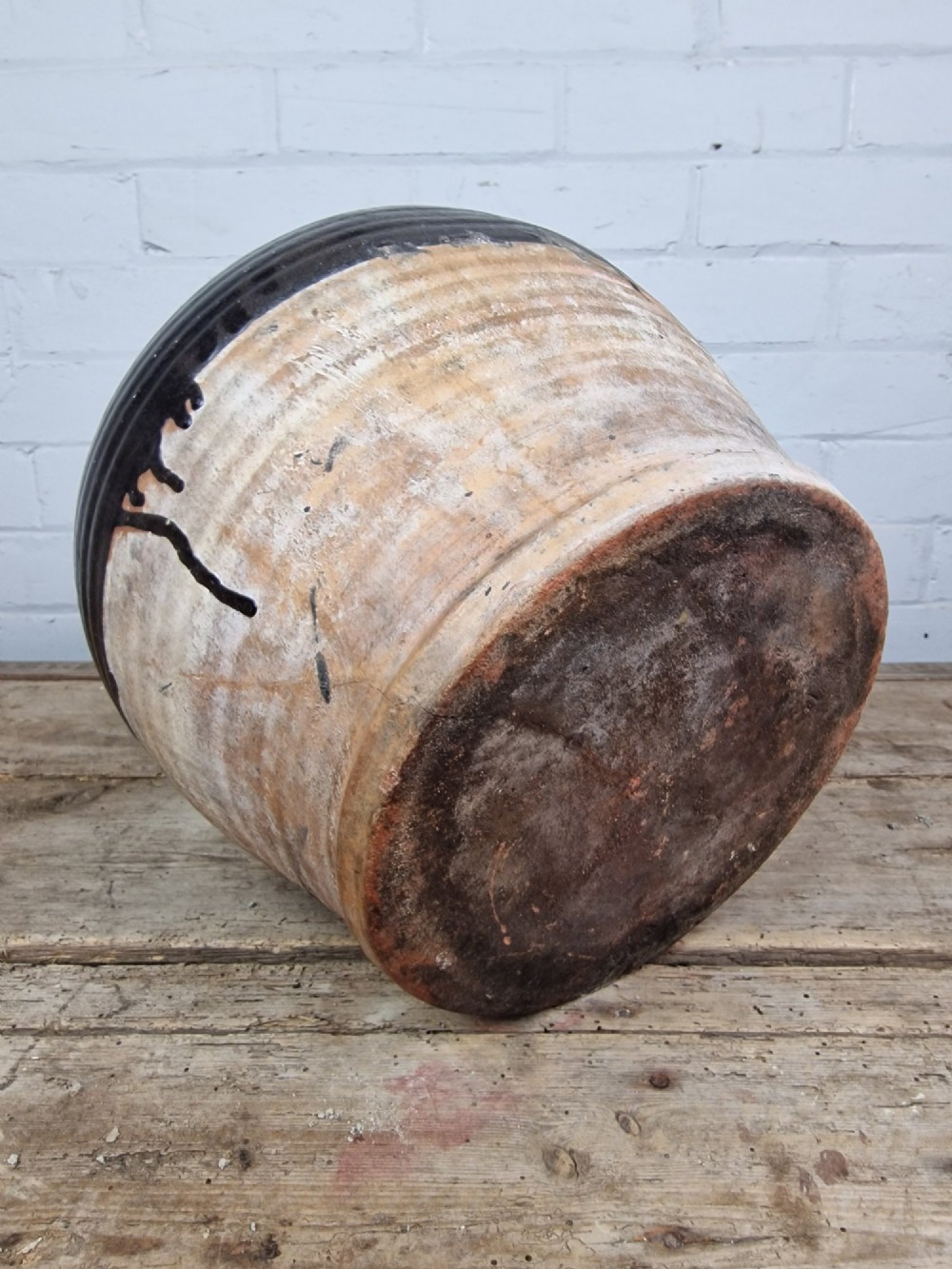 An antique late 18th or early 19th-century earthenware slipware jug featuring a dark brown glazed upper body and a textured terracotta lower base. View X