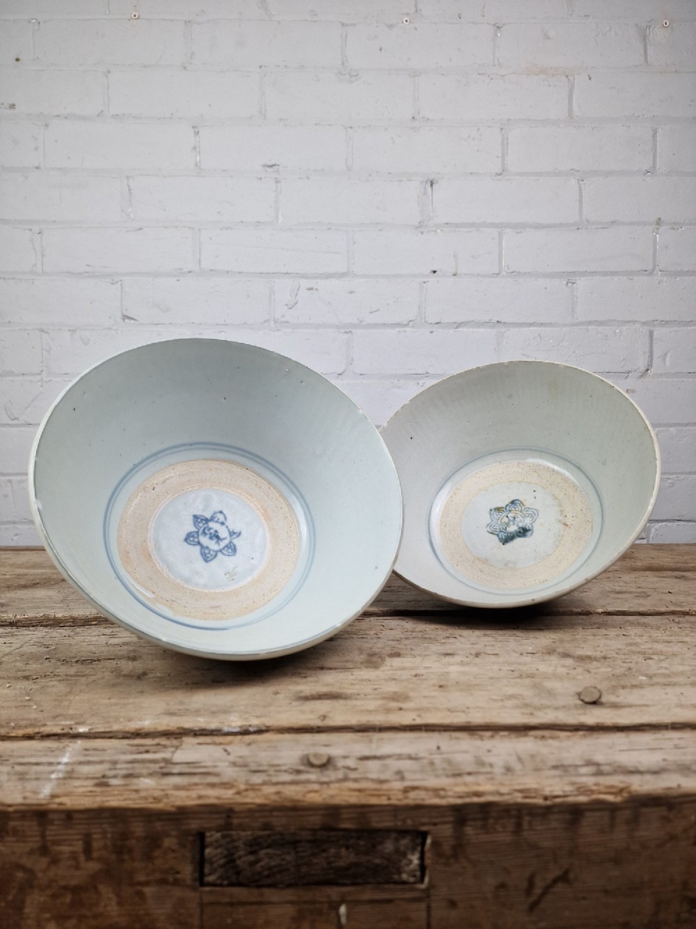 A pair of round Chinese provincial porcelain bowls featuring underglaze blue character motifs around the exterior on an off-white surface. View IV