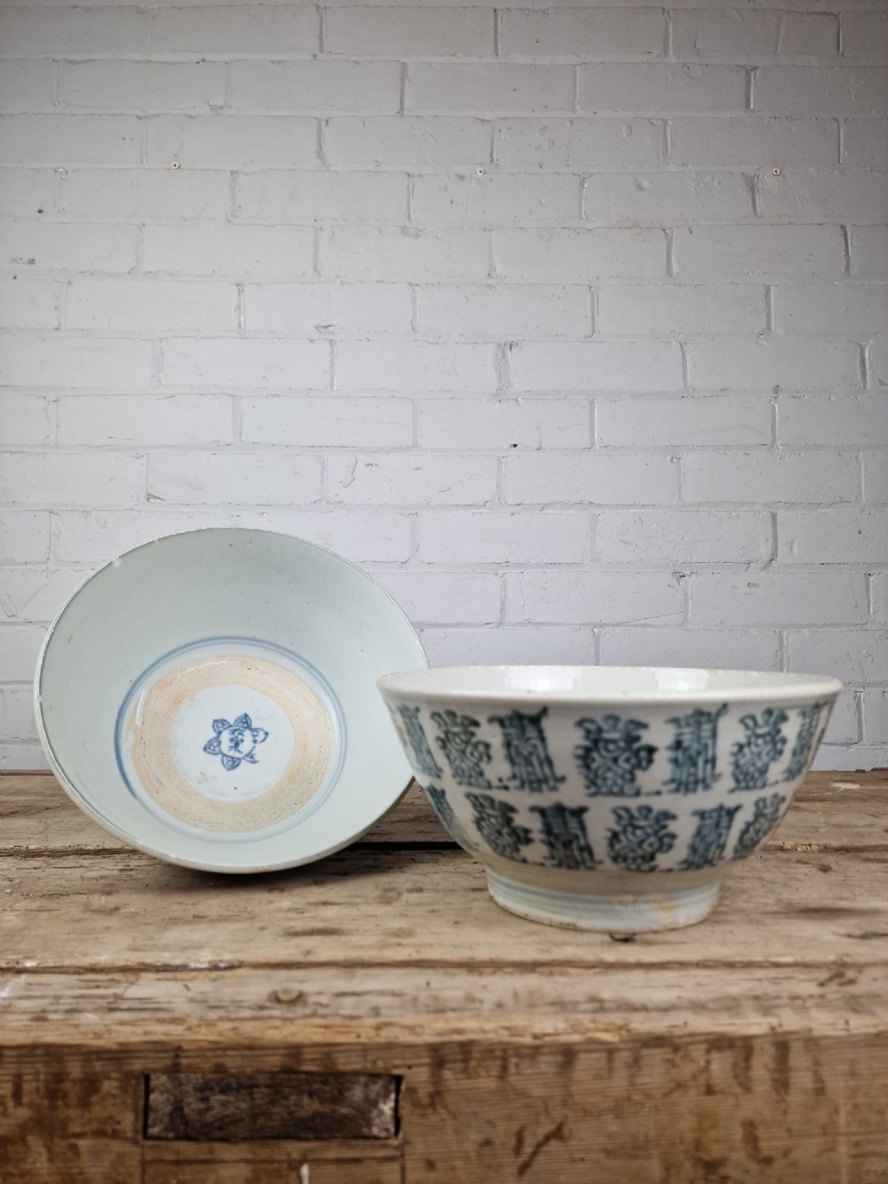 A pair of round Chinese provincial porcelain bowls featuring underglaze blue character motifs around the exterior on an off-white surface. View V