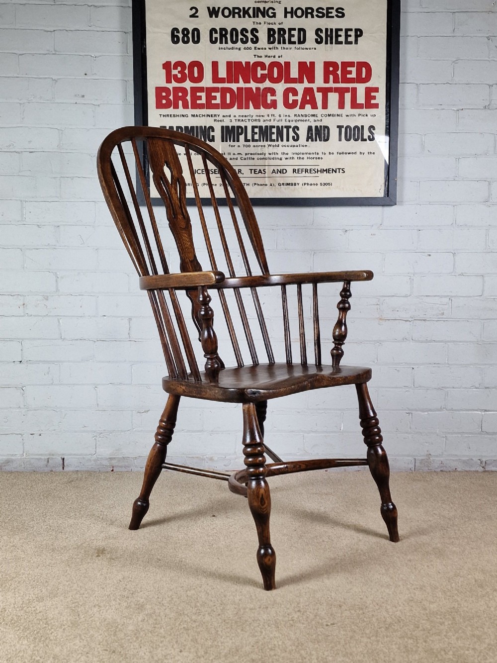 A 19th-century dark wooden Lincolnshire Windsor armchair featuring a hoop back, central pierced splat, turned spindles, and turned legs. View II