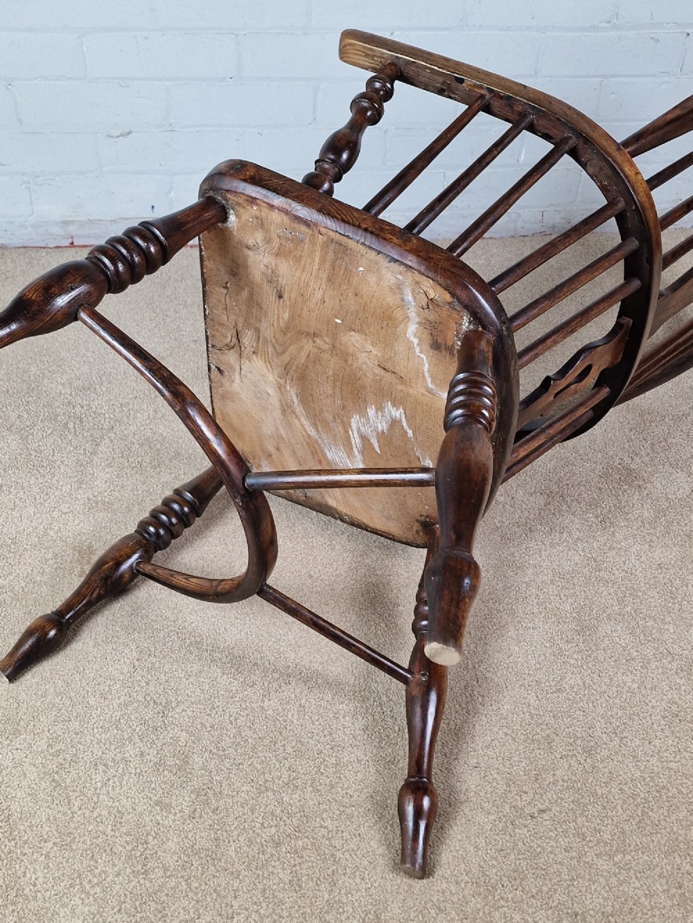 A 19th-century dark wooden Lincolnshire Windsor armchair featuring a hoop back, central pierced splat, turned spindles, and turned legs. View VI