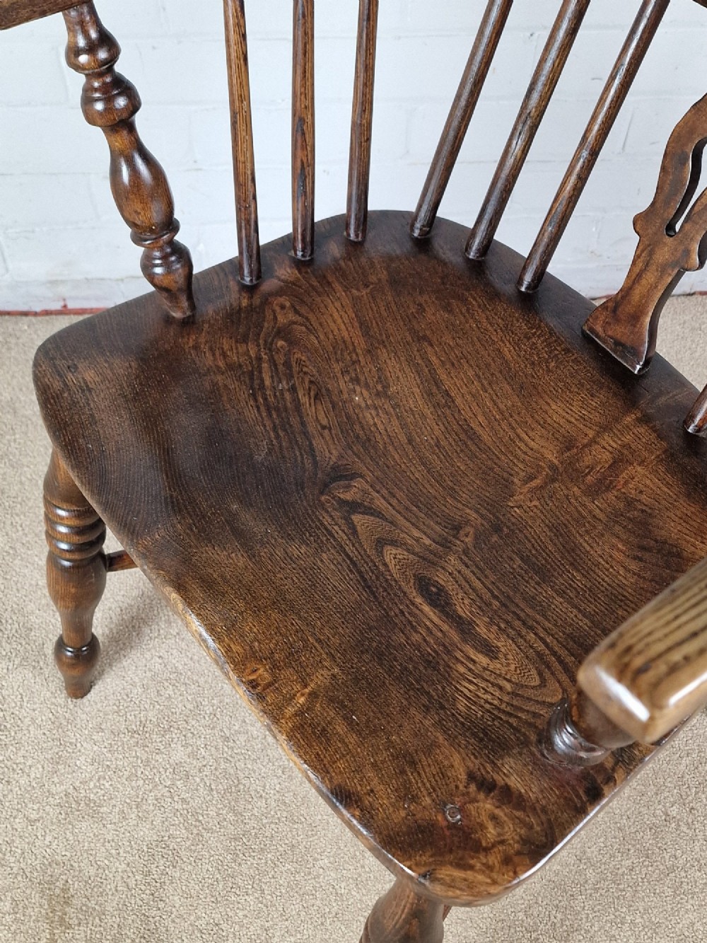 A 19th-century dark wooden Lincolnshire Windsor armchair featuring a hoop back, central pierced splat, turned spindles, and turned legs. View VII