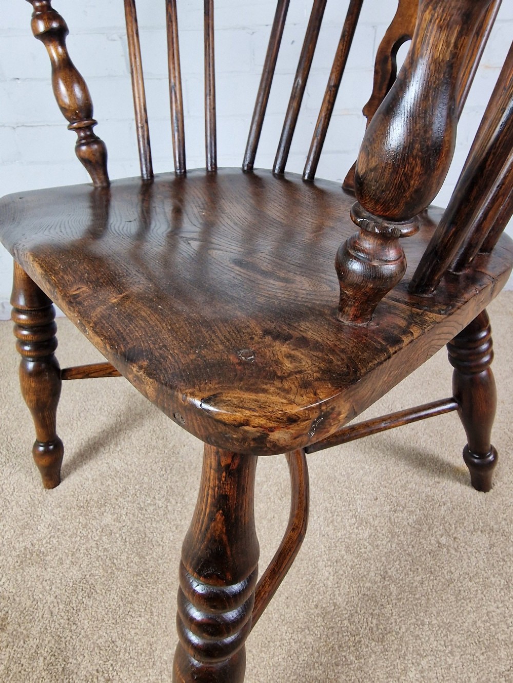 A 19th-century dark wooden Lincolnshire Windsor armchair featuring a hoop back, central pierced splat, turned spindles, and turned legs. View VIII