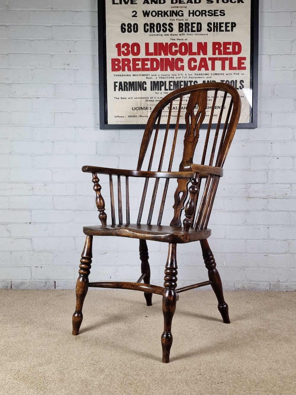 A 19th-century dark wooden Lincolnshire Windsor armchair featuring a hoop back, central pierced splat, turned spindles, and turned legs.
